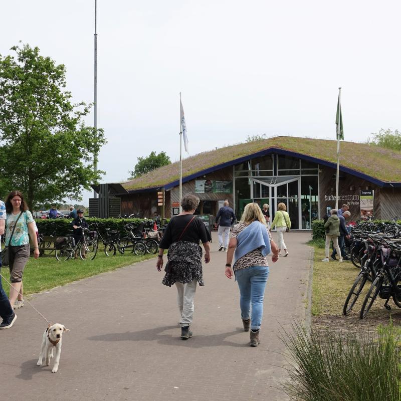 Mensen lopen naar en weg van Buitencentrum De Pelen