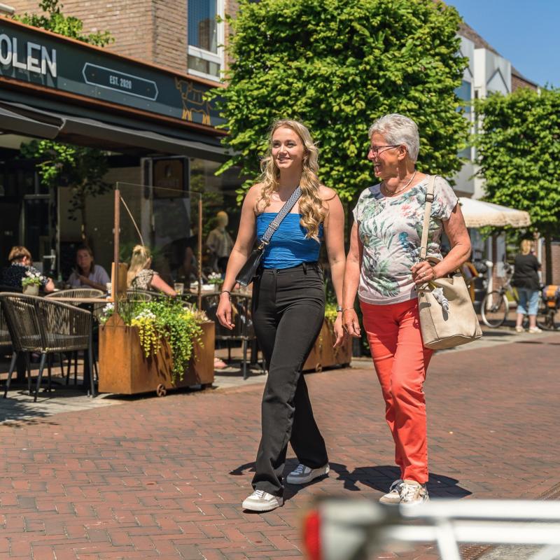 Jongere en oudere vrouw wandelen in dorpse winkelstraat