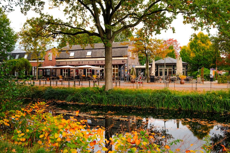 Historisch gebouw met terras aan water met gevallen herfstbladeren