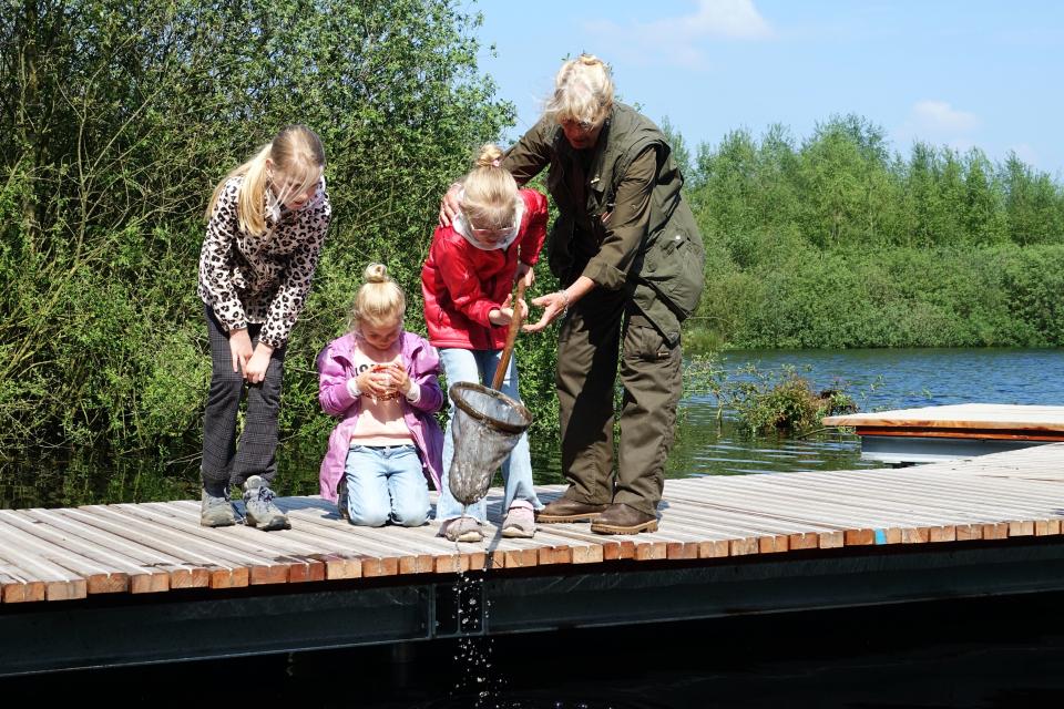 Kinderen en gids op vlonder aan water met schepnetten en loeppotjes