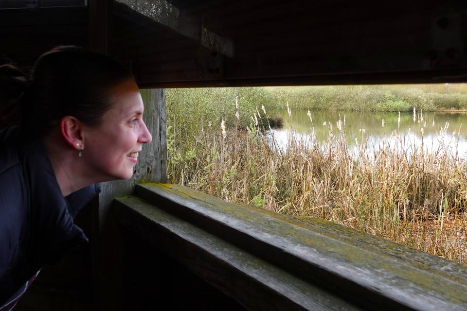 Vrouw kijkt naar landschap door houten open raam