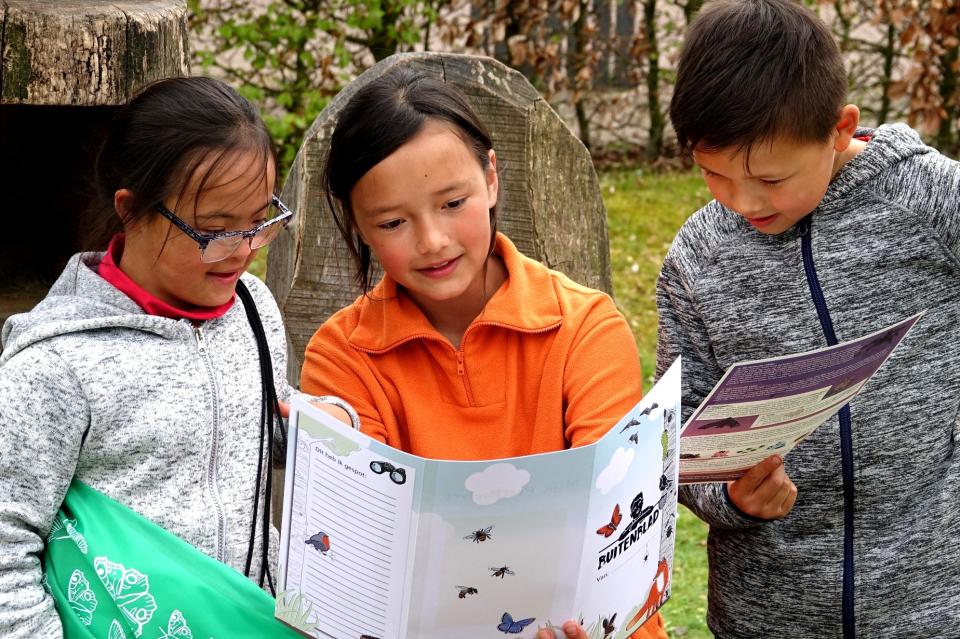 Kinderen met opdrachtenboekje in de natuur