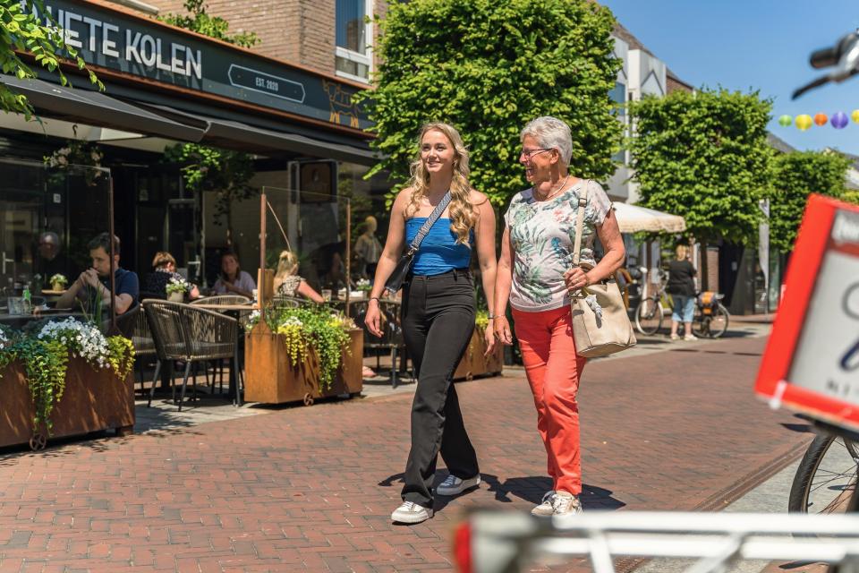 Jongere en oudere vrouw wandelen in dorpse winkelstraat