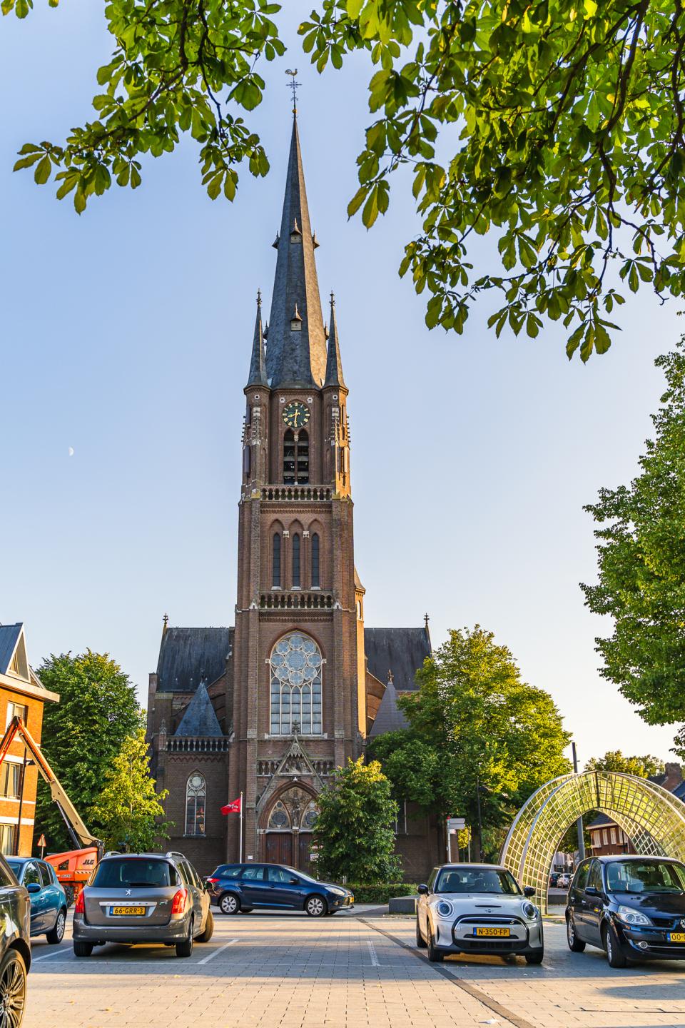 Kerk tussen bomen en straat met auto's
