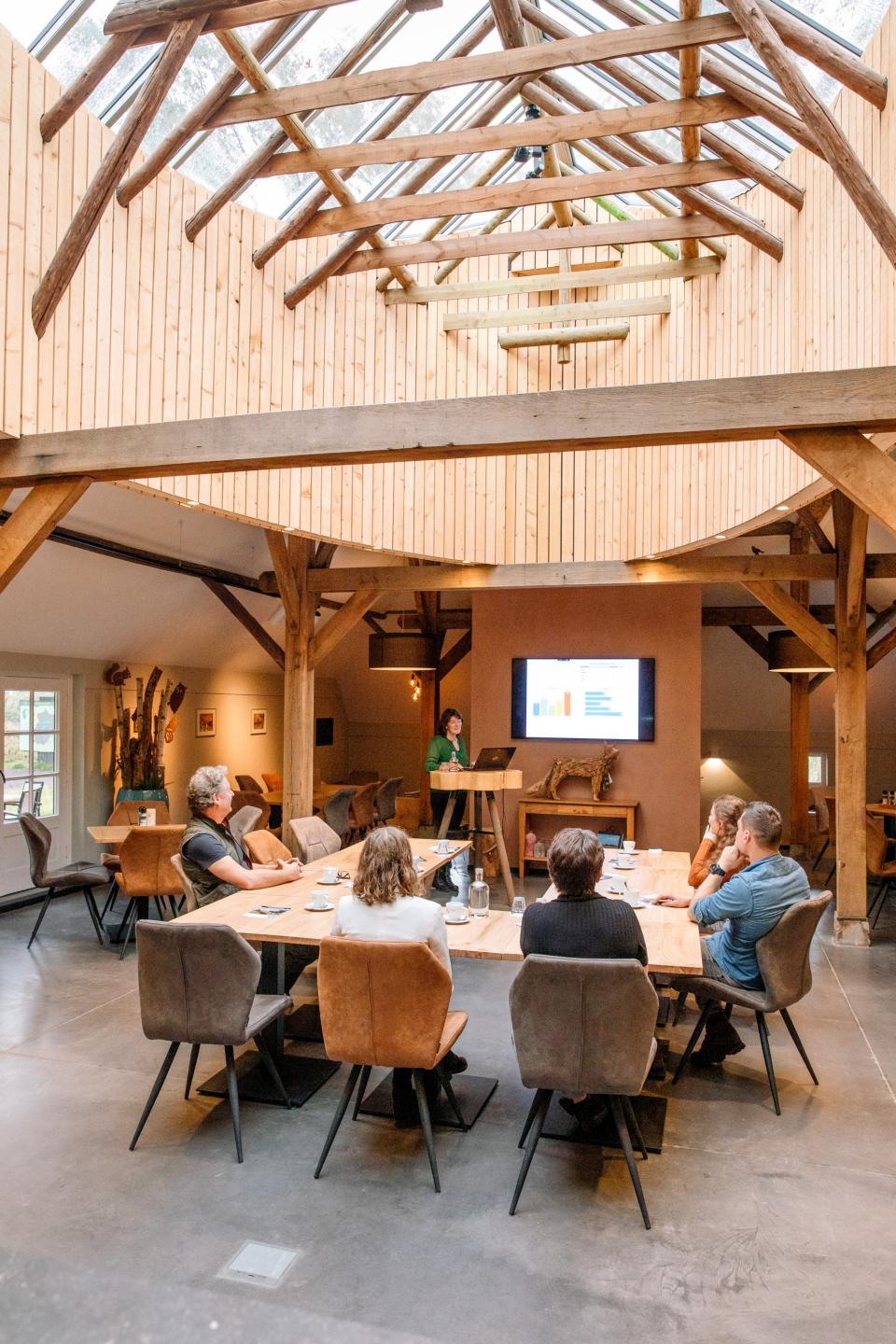 Mensen aan tafel die naar persoon kijken die presenteert met een tv-scherm