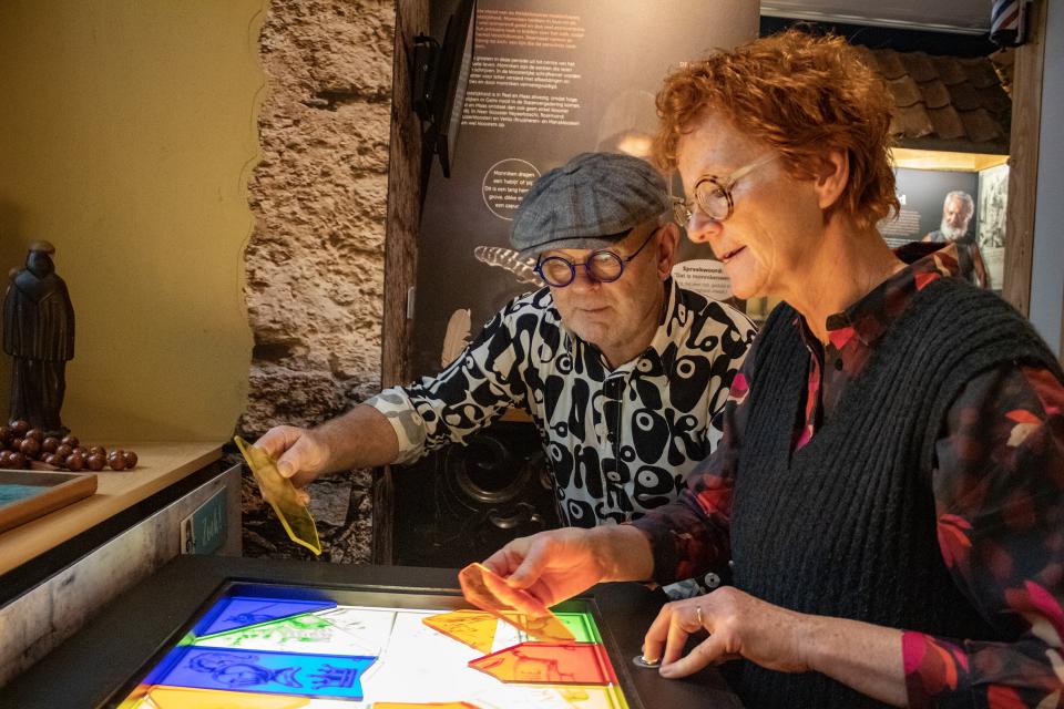 Man en vrouw leggen gekleurd glas op lichtplaat