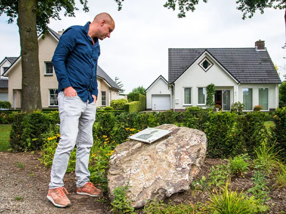 Man kijkt naar plaat op steen